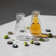 Upside down beer glasses flat lay with hops and bottle caps on concrete surface